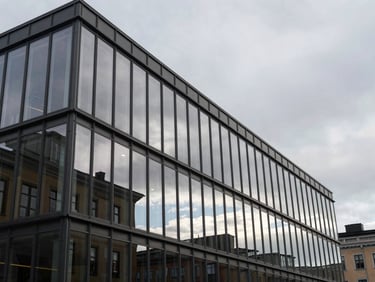 Crisp overcast Nordic daylight reflecting off a modern glass office facade in Helsinki, architectural details, cool steel gray tones.