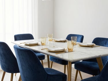 Bright editorial dining room staging, elegant marble table with brass tableware, deep blue velvet chairs, soft morning light, 35mm lens