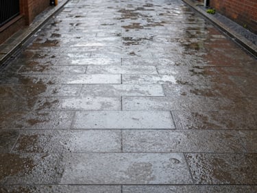 Wide environmental shot of a pristine, freshly cleaned block-paving driveway in a Liverpool suburb, wet stones reflecting bright overcast daylight, 35mm.
