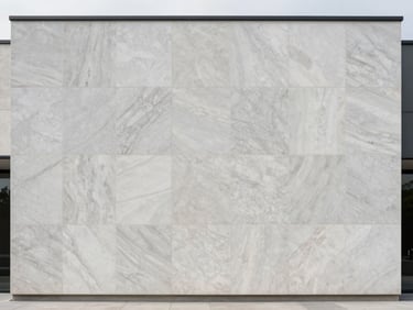 Architectural elevation photograph of large-format quartzite facade panels installed on a contemporary building exterior, shot straight-on in overcast daylight showing stone joint precision and surface texture