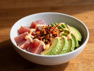 A vibrant poke bowl with fresh ahi tuna, avocado, and spicy mayo, bright editorial food lighting, clean composition, 35mm.
