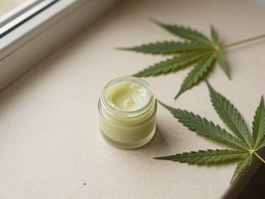 Overhead flatlay of a small jar of botanical balm next to dried hemp leaves, soft natural window light, earthy green and sand tones