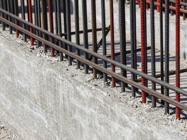 Close-up of freshly poured concrete wall with steel reinforcement bars, hard direct daylight, high contrast