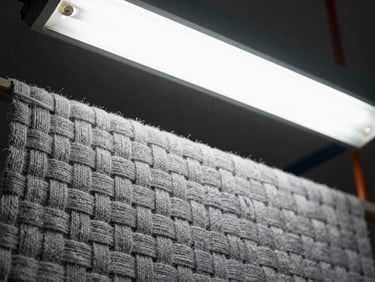 Close-up of woven gray textile threads under high-contrast industrial light.