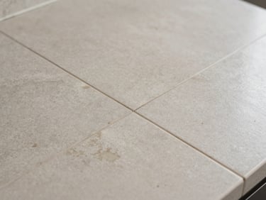Tile countertop with discolored grout lines and a hairline crack visible in one tile, consistent even light, tight crop, no props or accessories