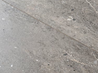 Natural travertine floor tile with white efflorescence mineral deposits visible on the surface, even overhead light, tight crop showing the stone texture, no people