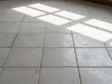Medium shot of a restored porcelain floor tile expanse — grout lines clean and consistent, tile surface free of haze, natural window light raking across the surface to show even texture