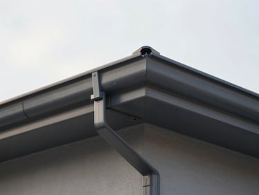 Close-up detail shot of perfect mitered corners and clean joints on a newly installed dark gray aluminum gutter system, soft morning light, 35mm