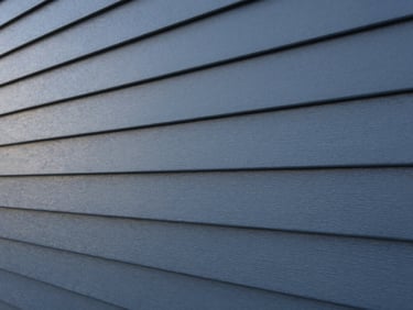 Close-up of pristine modern siding panels in deep slate blue-gray, perfect alignment, soft early morning light, architectural detail, 35mm