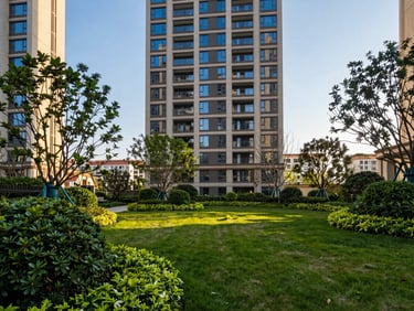 Close-up of vibrant green foliage and trees in a meticulously landscaped garden within a high-rise residential complex, warm natural light.