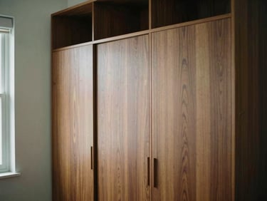 A beautifully finished built-in wardrobe in a modern bedroom, soft residential light, rich walnut tones, warm editorial photography.