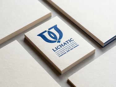 Overhead flat-lay of custom corporate stationery sets, heavy-weight paper stocks with deep blue ink debossing, natural workshop side-light highlighting textures