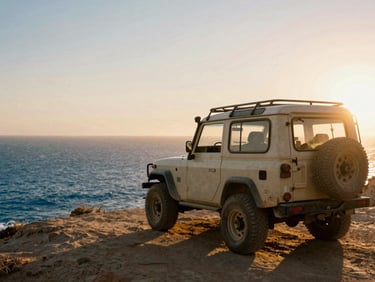A dusty off-road vehicle parked on a cliff overlooking the deep blue sea in Baja California, warm sunset flare