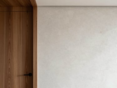 Meticulous interior fit-out showing a flawless transition between walnut wood paneling and microcement wall, clean minimalist architecture.