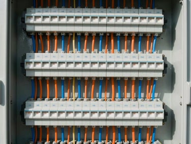 Close-up of a perfectly organized industrial electrical panel, neat parallel wiring in orange and blue channels, switches labeled clearly, high-contrast work light