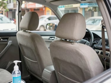 Clean car interior, focusing on the back seats and headrests, bright natural light, showing sanitizing wipes on the dashboard, 35mm.