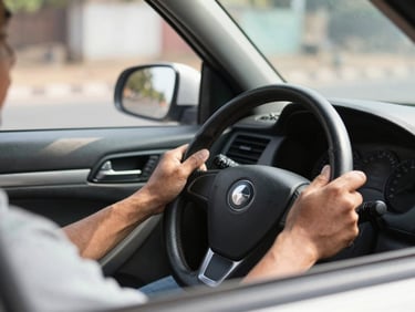 Close-up of a professional driver's hands on a steering wheel, clear view of the road ahead, bright daylight, 35mm.