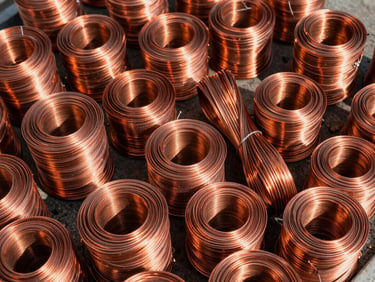 Sharp close-up of sorted bright copper wire bundles in an organized industrial scrap yard, harsh direct daylight, high contrast, 35mm