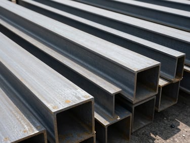 Heavy structural steel beams and plates organized in a processing zone, industrial documentary photography, 35mm
