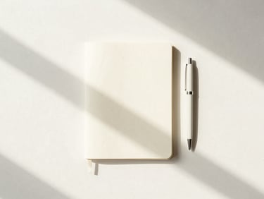 Minimalist overhead flat-lay of a clean workspace with a notebook, pen, and soft morning shadows on a cream surface, low-saturation pastel tones