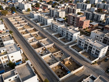 Aerial view looking down at a kanal-sized plot in WAPDA Town housing society, boundary walls partially constructed, organized street grid visible around the plot, clear sky, architectural documentation style, no people