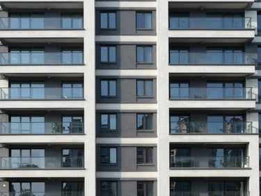 Modern residential building facade photographed straight-on in morning daylight, white plaster and glass, no people