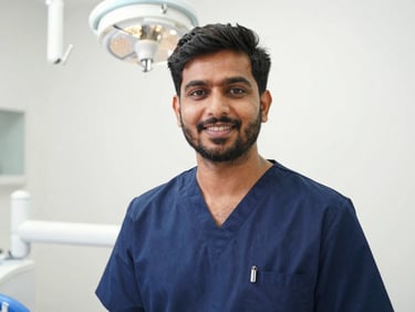 Professional medium portrait of Dr. Aman Sharma in clean clinical attire, bright natural daylight, warm and confident expression, sterile dental office background.