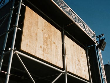 Extreme close-up of heavy steel scaffolding and custom wood paneling on a festival stage, sharp spotlight, industrial texture