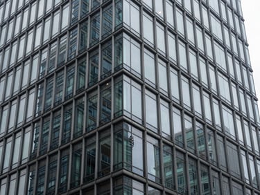 Abstract architectural crop of a high-end steel and glass skyscraper corner, cool diffused daylight, sharp high-contrast shadows, 35mm photography