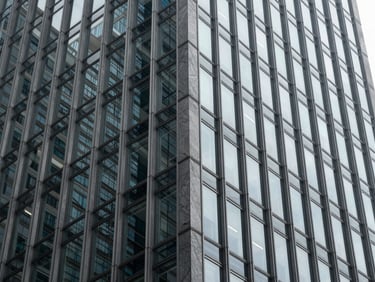 Abstract close-up of a modern steel and glass skyscraper facade, sharp architectural angles, cool diffused daylight, high contrast shadows