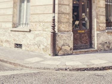 Close-up of a watercolor painting showing a quiet Parisian street corner, textured paper grain, soft daylight