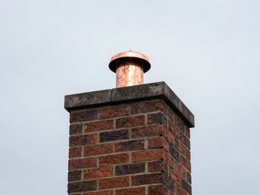 Newly installed copper chimney cap on a brick chimney, against a New England sky.
