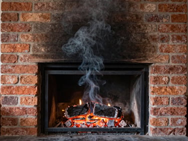 Smoke swirling upwards in a clean fireplace, illustrating good draft, warm indoor hearth light.