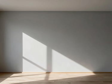 Wide architectural angle of a minimalist Madrid living room, natural daylight raking across a seamless warm grey Mortex wall, shadow play, negative space on the left.