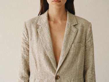 Minimalist unposed fashion portrait of a woman wearing a relaxed linen blazer, soft diffused daylight, warm earth tones, 35mm film