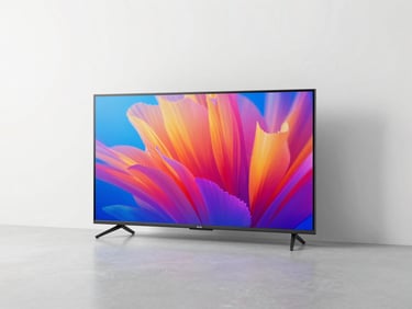 A high-end smart TV displaying vibrant colors on a clean white wall, neutral studio lighting