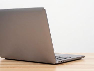 Close-up of a modern sleek metallic laptop open on a wooden desk, bright studio lighting