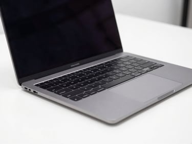 Close-up of a sleek dark gray laptop open on a clean white desk, bright studio lighting, sharp focus