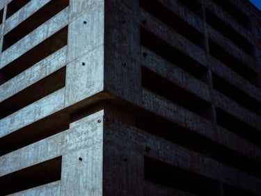Brutalist concrete monolith with embedded security sensors, low-key, high-contrast, cold blue light, deep shadows, 35mm