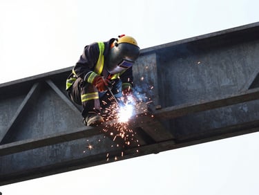 Welder in high-vis gear executing structural welding on a crane girder, bright sparks flying against dark steel background, high contrast.