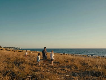Wide cinematic landscape of a family walking along a pristine wild coastline, soft natural warm light, editorial travel style.