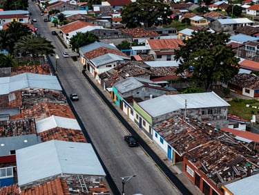 Aerial view of Puerto Araujo Colombia small municipality streets with fiber conduit lines along buildings, cool daylight, precise technical composition