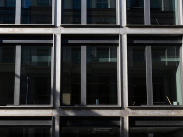 High-contrast architectural crop of clean steel and glass facade on Regent Street, sharp shadows, daylight.
