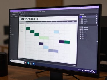 Structured content calendar interface with production workflows and asset pipelines on a sleek dark monitor, purple reflections.