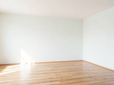 Empty, freshly cleaned room with gleaming hardwood floors and white walls, bright natural light, showing pristine condition, high-key interior.