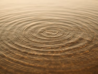 Ripples in clear water under soft golden sunlight, warm natural daylight, minimalist composition
