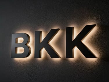 Backlit 3D letters mounted on a dark textured wall, casting a soft halo glow