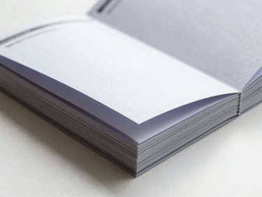 Close-up flat lay of folded brochures and tri-fold collateral stacked at a slight angle, crisp fold creases visible, bright daylight studio, no people