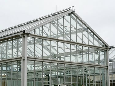 Architectural close-up of a modern glass greenhouse structure, showing clean lines and diffused interior light.