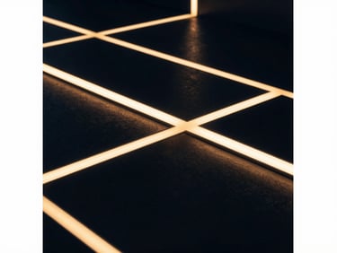 Abstract geometric light patterns on a polished dark surface, creating a sense of depth and structure, low-key dramatic interior lighting, warm highlights, editorial corporate photography, deep navy and warm gold tones, high contrast.